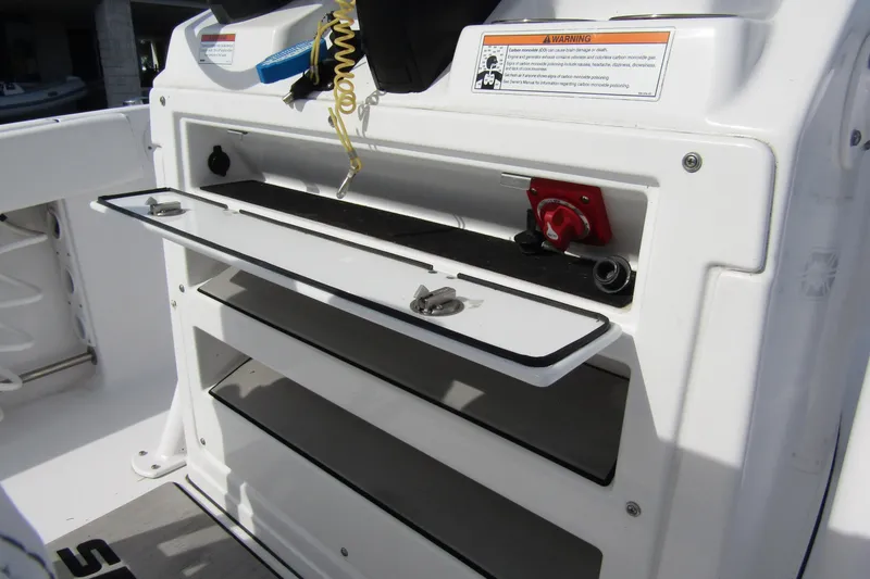 Slide: The Image of 2023 Sportsman Open 212 Center Console storage compartment with safety warning label. - 26