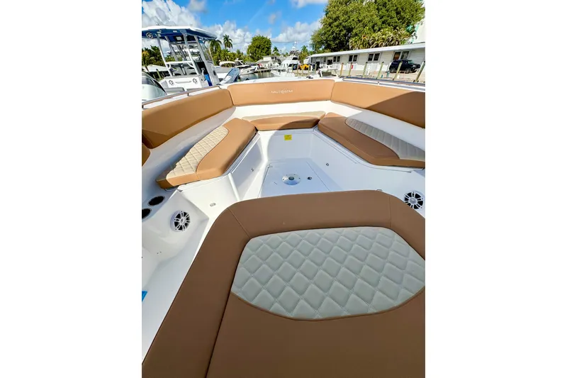 Slide: The Image of 2026 NauticStar 332 Offshore boat interior with tan and white seating, docked outdoors. - 10