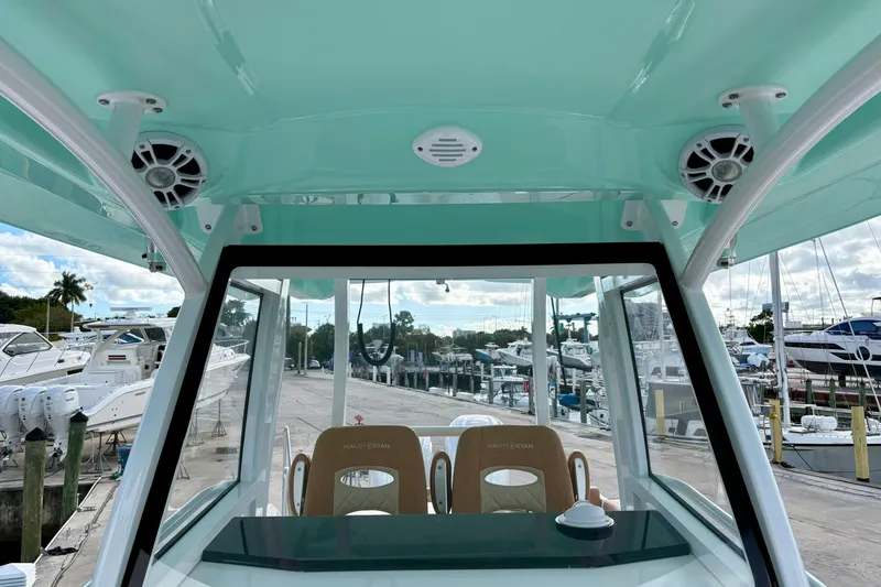 Slide: The Image of 2026 NauticStar 332 Offshore boat interior with speakers and seating at a marina. - 12