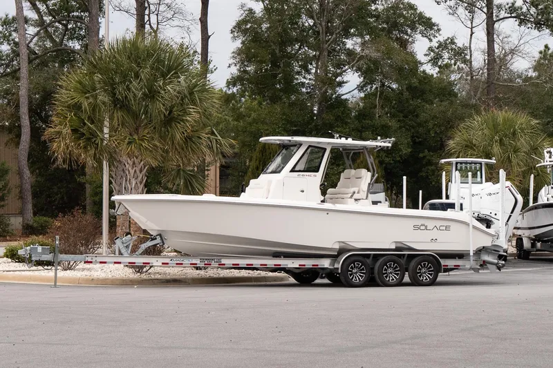 The Image of 2026 Solace 28 HCS boat on trailer, parked near palm trees. - 1