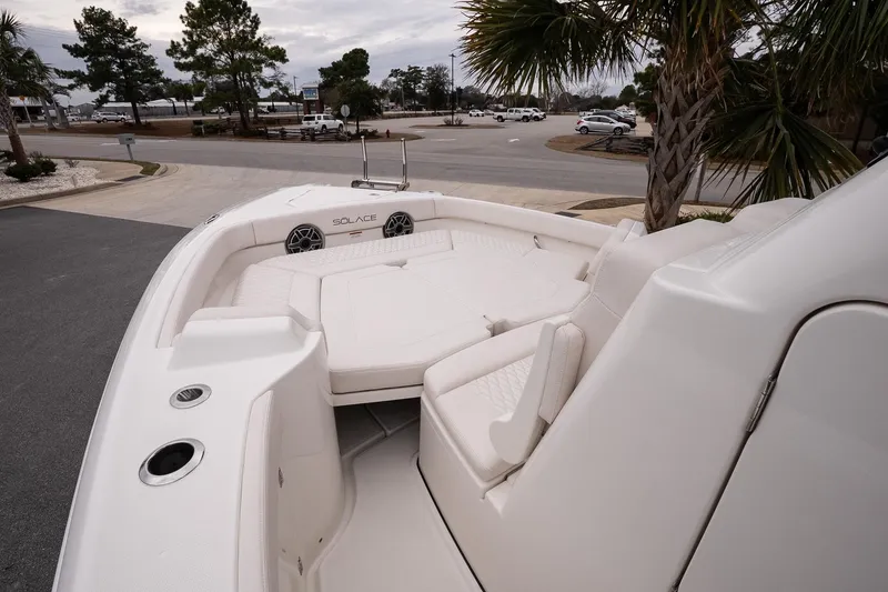 Slide: The Image of 2026 Solace 28 HCS boat interior with white seating and speakers, parked near palm trees. - 22