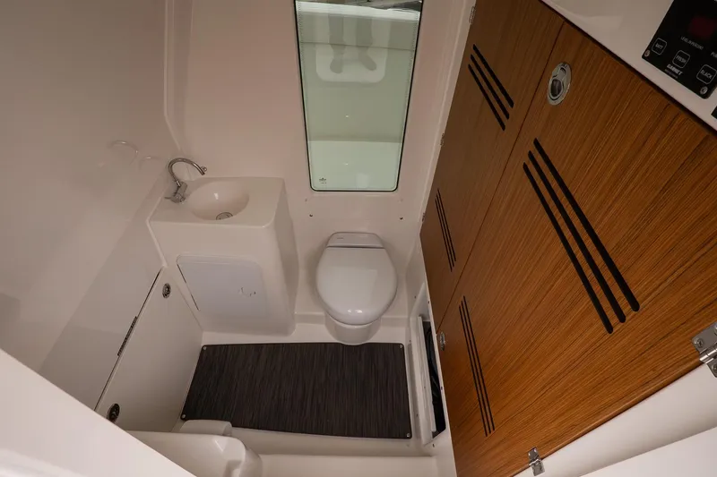 Slide: The Image of Modern bathroom in 2026 Solace 28 HCS boat with sink, toilet, and wooden cabinetry. - 28