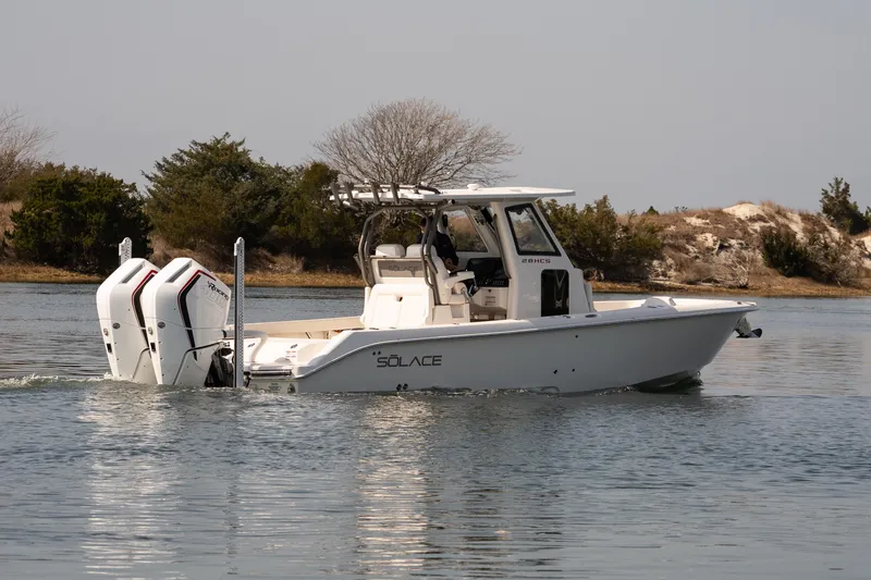 Slide: The Image of 2026 Solace 28 HCS boat cruising on calm water, featuring dual outboard engines. - 30
