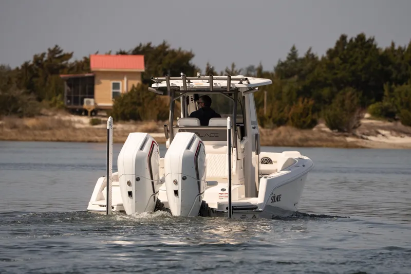 Slide: The Image of 2026 Solace 28 HCS boat cruising on calm water near a coastal house. - 31