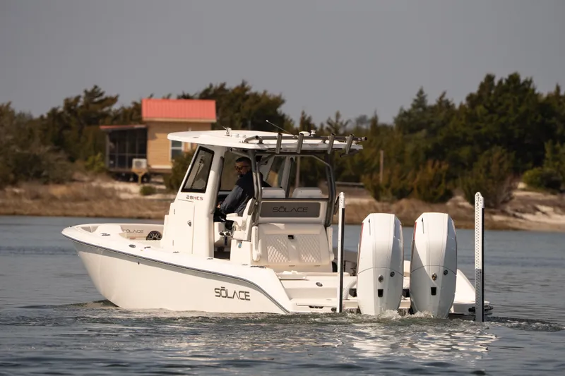 Slide: The Image of 2026 Solace 28 HCS boat cruising on calm water near a wooded shoreline. - 32
