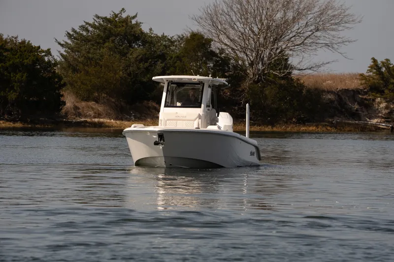 Slide: The Image of 2026 Solace 28 HCS boat cruising on calm water near a wooded shoreline. - 34
