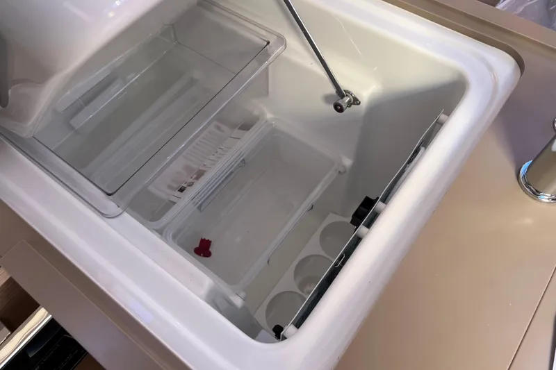 Slide: The Image of 2026 Dufour 37 yacht interior fridge with open lid and storage compartments. - 15