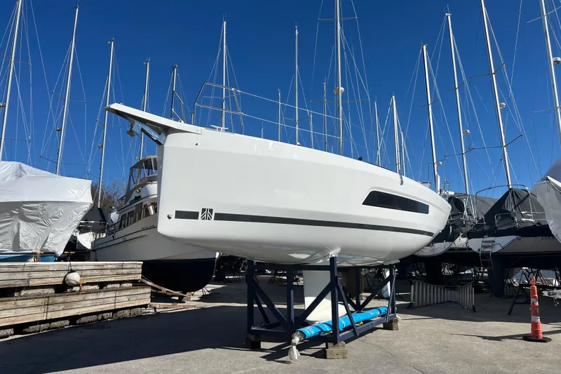Slide: The Image of 2026 Dufour 37 yacht on dry dock, surrounded by sailboats under clear blue sky. - 4