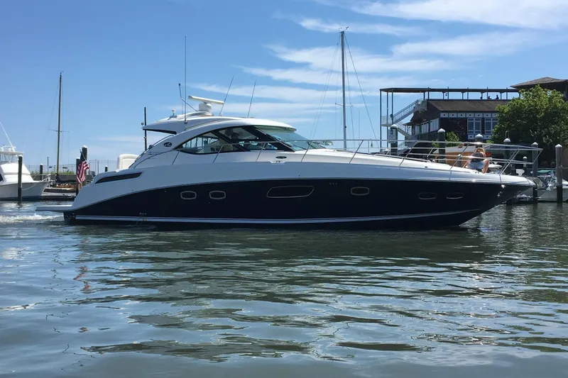 The Image of 2009 Searay 43 Sundancer yacht docked in a marina under a clear blue sky. - 0