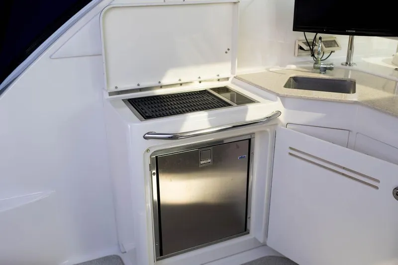 Slide: The Image of 2009 Searay 43 Sundancer yacht kitchenette with grill, sink, and stainless steel fridge. - 10