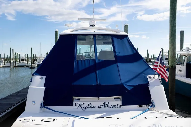 Slide: The Image of 2009 Searay 43 Sundancer yacht docked with blue cover and American flag. - 2