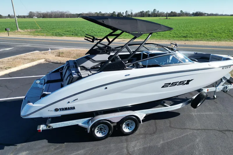 Slide: The Image of 2024 Yamaha Boats 255XE on trailer, sleek design, parked near green field. - 20