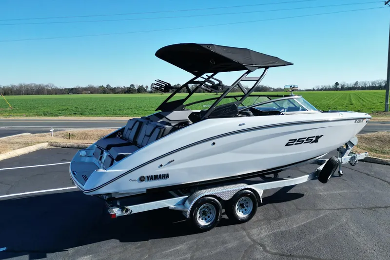 Slide: The Image of 2024 Yamaha Boats 255XE on trailer, parked near green field under clear sky. - 5