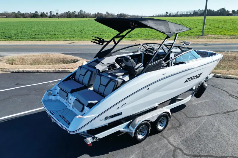Slide: The Image of 2024 Yamaha Boats 255XE on trailer, sleek design, parked near green field. - 21
