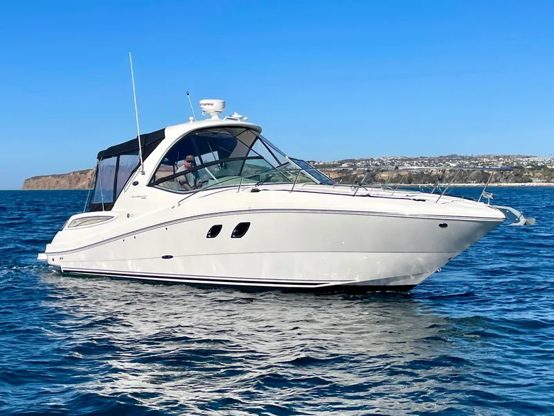 Slide: The Image of 2014 Sea Ray 330 Sundancer cruising on open water under clear blue skies. - 2