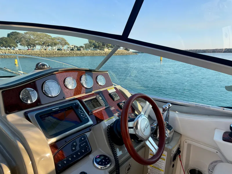 Slide: The Image of 2014 Sea Ray 330 Sundancer cockpit with navigation instruments, steering wheel, and scenic water view. - 27