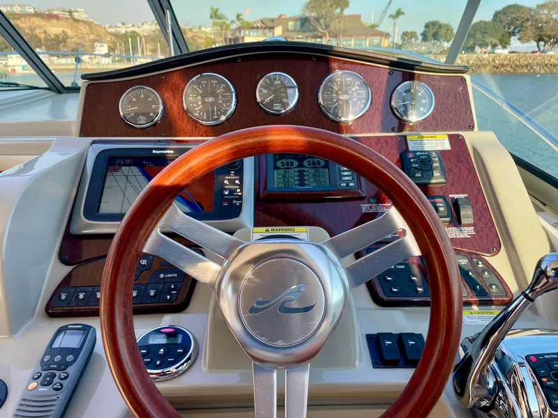 Slide: The Image of 2014 Sea Ray 330 Sundancer helm with wood steering wheel and navigation instruments. - 32