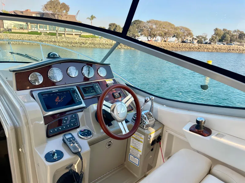 Slide: The Image of 2014 Sea Ray 330 Sundancer cockpit with modern controls and scenic waterfront view. - 37