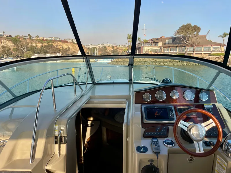 Slide: The Image of 2014 Sea Ray 330 Sundancer cockpit with steering wheel and control panel, docked in a marina. - 38