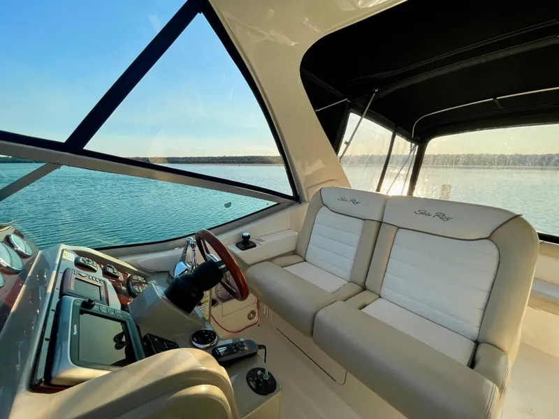 Slide: The Image of 2014 Sea Ray 330 Sundancer interior with beige seating and helm, overlooking serene water. - 41