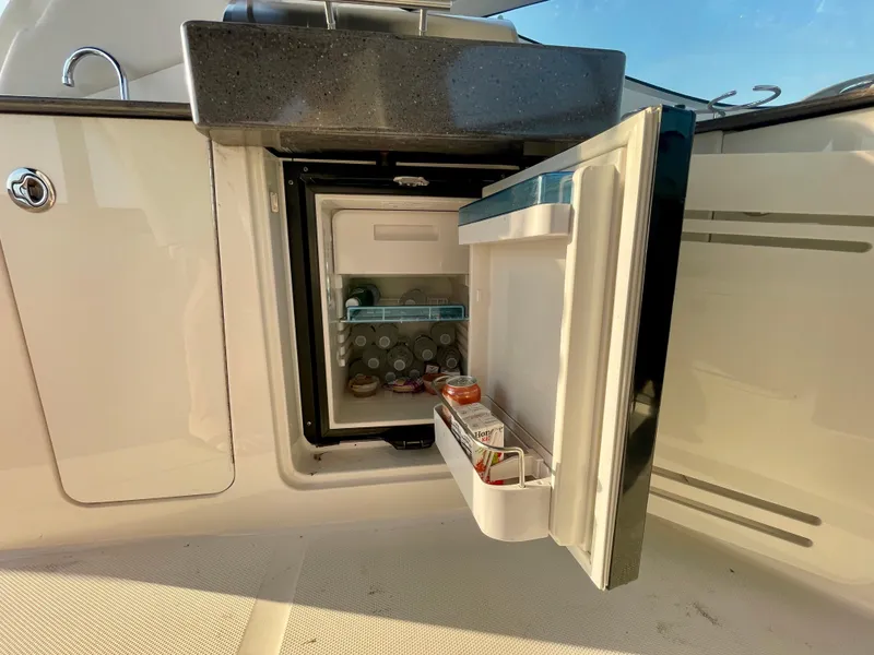 Slide: The Image of Open mini fridge on 2014 Sea Ray 330 Sundancer boat, stocked with beverages. - 45