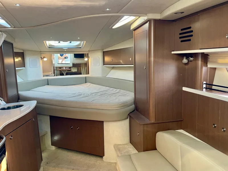 Slide: The Image of 2014 Sea Ray 330 Sundancer cabin interior with bed, wood cabinetry, and seating area. - 7