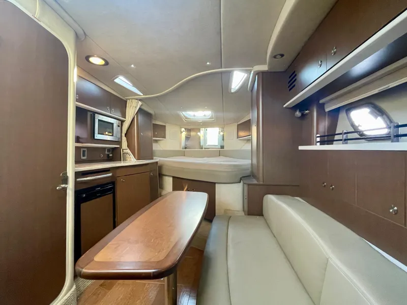 Slide: The Image of 2014 Sea Ray 330 Sundancer cabin interior with kitchen, seating, and bed. - 8