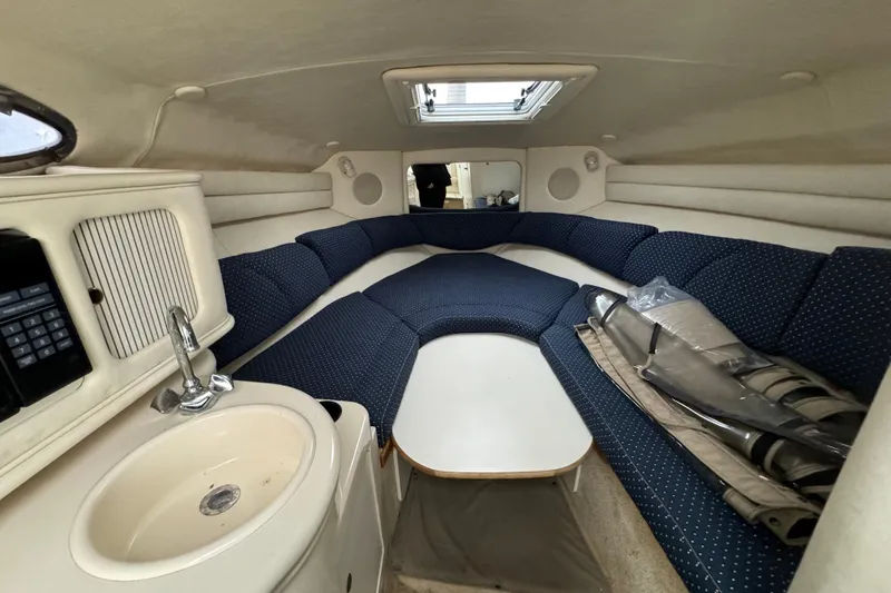 Slide: The Image of 2000 Sea Ray 245 Weekender cabin interior with blue seating, sink, and storage. - 3
