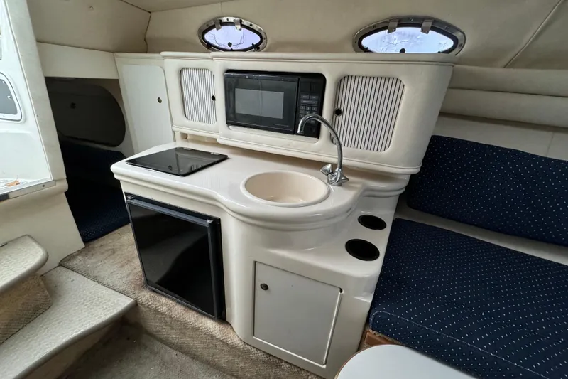 Slide: The Image of 2000 Sea Ray 245 Weekender cabin interior with kitchenette, sink, and seating area. - 5