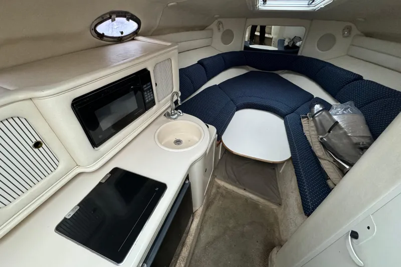 Slide: The Image of 2000 Sea Ray 245 Weekender cabin interior with kitchenette and seating area. - 6