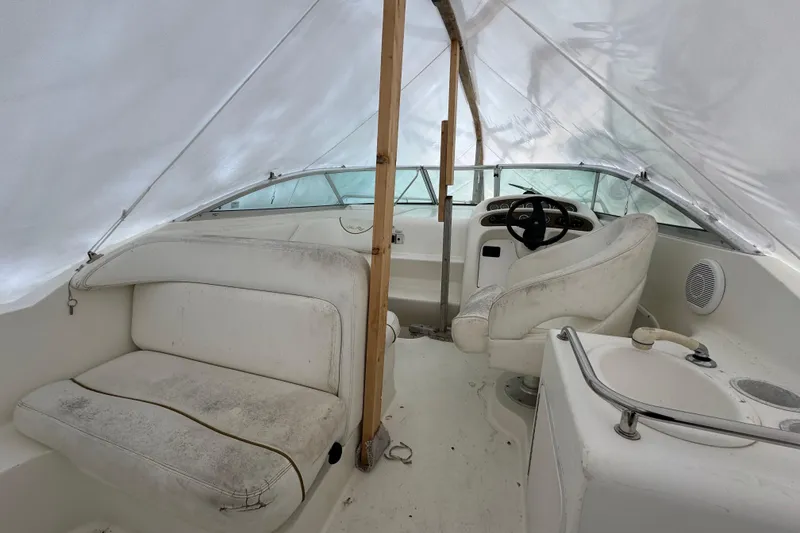 Slide: The Image of 2000 Sea Ray 245 Weekender boat interior with white seating and steering wheel. - 8