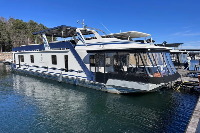 The Image of 1996 Sumerset 16x83 houseboat docked on a sunny day, featuring a spacious upper deck. - 0
