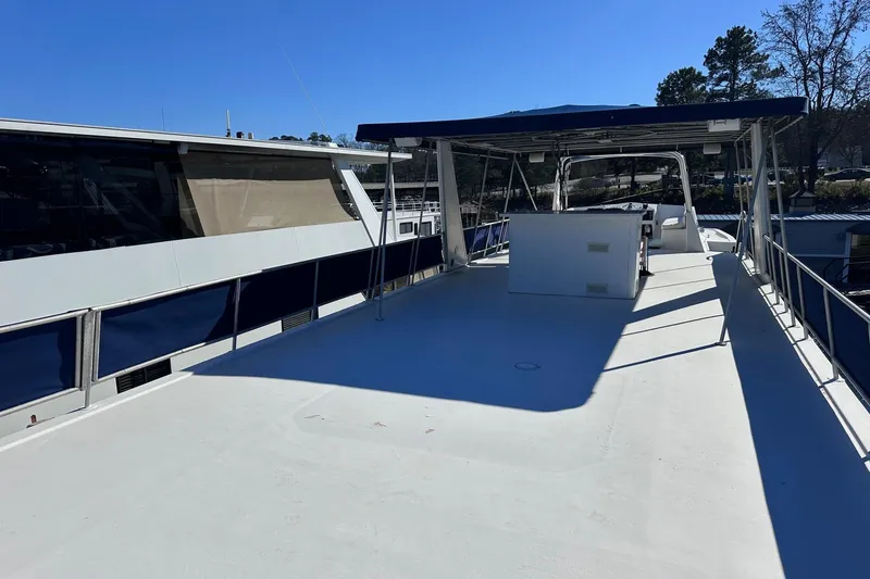 Slide: The Image of 1996 Sumerset 16x83 houseboat with spacious upper deck and canopy, docked under clear blue sky. - 16