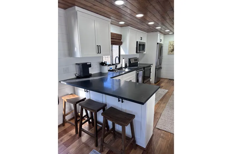 Slide: The Image of Modern kitchen in 1996 Sumerset 16x83 houseboat with sleek countertops and wooden stools. - 5