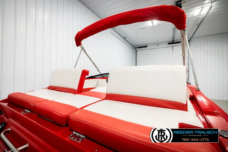 Slide: The Image of 2022 Crownline 220 LPX boat with red and white seating in a showroom. - 24
