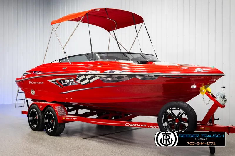 Slide: The Image of Red 2022 Crownline 220 LPX boat with trailer and canopy in showroom. - 3