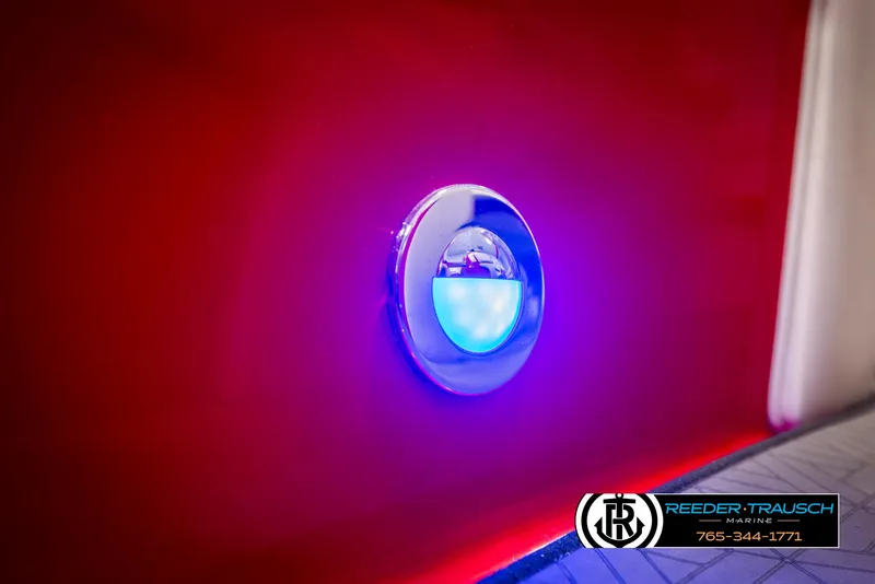 Slide: The Image of LED light on 2022 Crownline 220 LPX boat, glowing blue against red hull. - 37