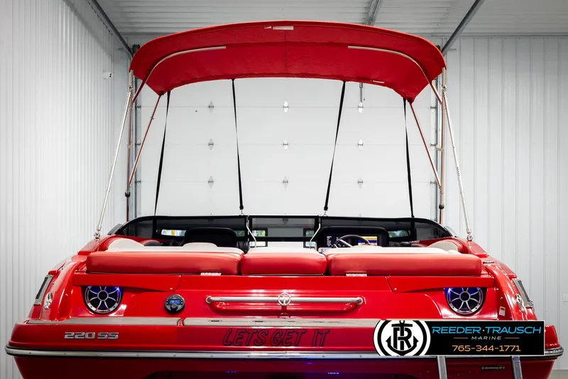 Slide: The Image of 2022 Crownline 220 LPX boat with red canopy in a storage facility. - 7