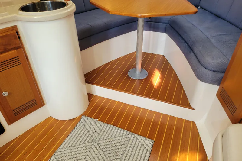 Slide: The Image of 1998 Cabo 31 Express interior with wood flooring, cushioned seating, and compact table. - 10