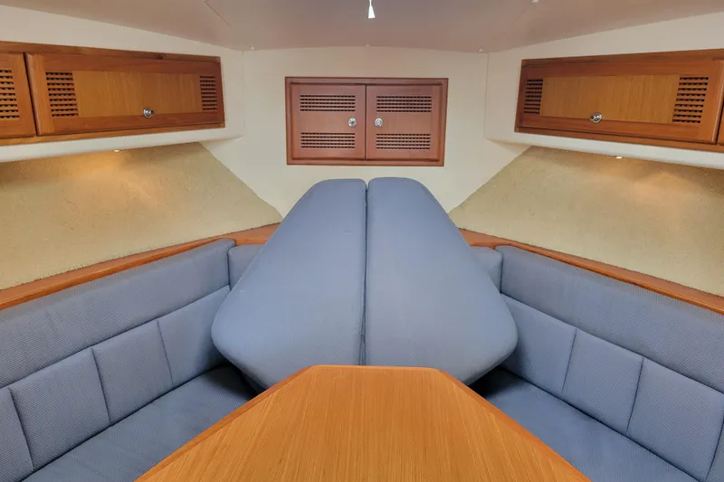 Slide: The Image of 1998 Cabo 31 Express cabin interior with blue seating and wooden cabinetry. - 16
