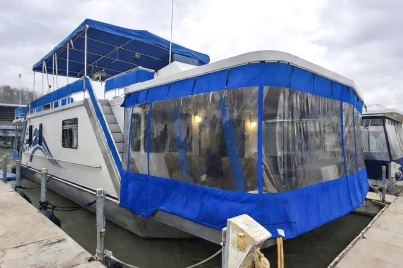 The Image of 1996 Lakeview 66 x 16 Widebody Houseboat with blue canopy docked at marina. - 0