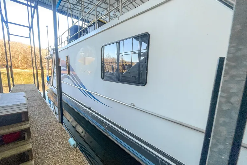 Slide: The Image of 1996 Lakeview 66 x 16 Widebody Houseboat docked, featuring blue wave design. - 12