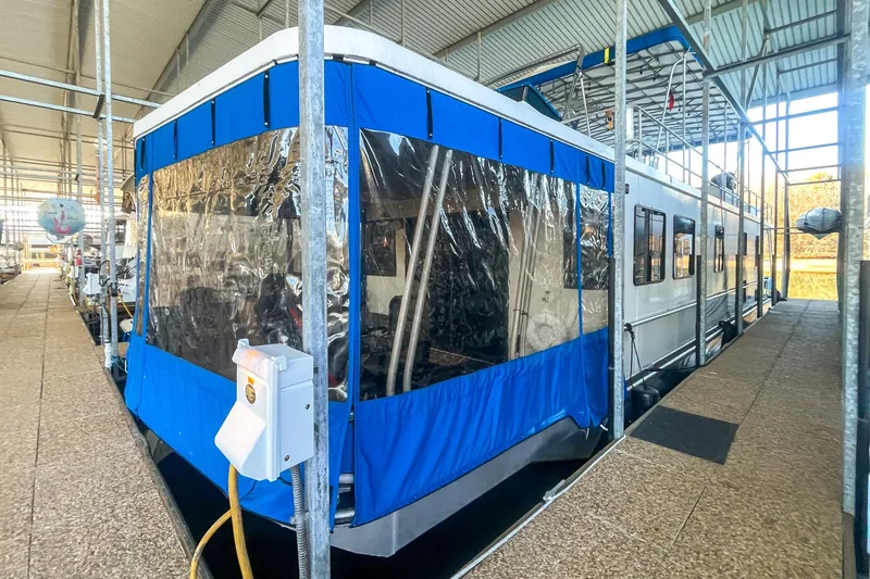 Slide: The Image of 1996 Lakeview 66 x 16 Widebody Houseboat docked with blue canopy in marina. - 2