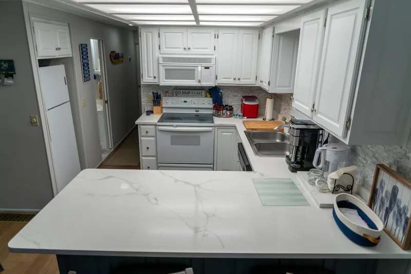 Slide: The Image of Modern kitchen in a 1996 Lakeview 66 x 16 Widebody Houseboat with white cabinetry and appliances. - 36