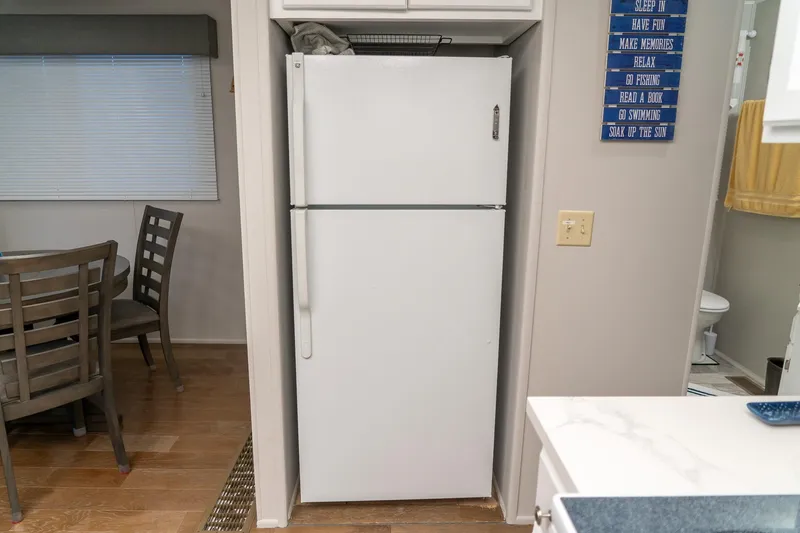 Slide: The Image of White refrigerator in a houseboat kitchen, adjacent to dining area and bathroom. - 46