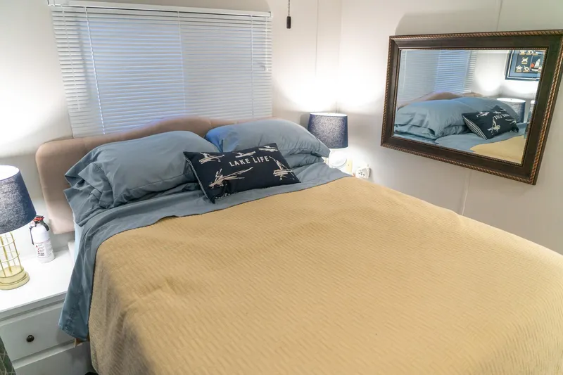 Slide: The Image of Cozy bedroom in 1996 Lakeview houseboat with mirror, lamp, and "Lake Life" pillow. - 65