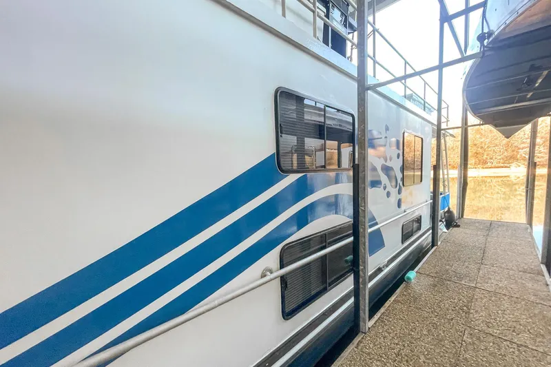 Slide: The Image of 1996 Lakeview 66 x 16 Widebody Houseboat docked, featuring blue wave design. - 7