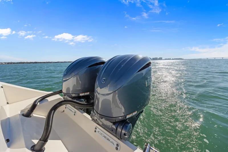 Slide: The Image of 2023 Cobia 301 Center Console with dual outboard engines on open water. - 24