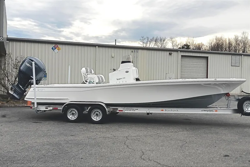 Slide: The Image of 2026 BlackJack 256 Bay boat on trailer, parked outside industrial building. - 1