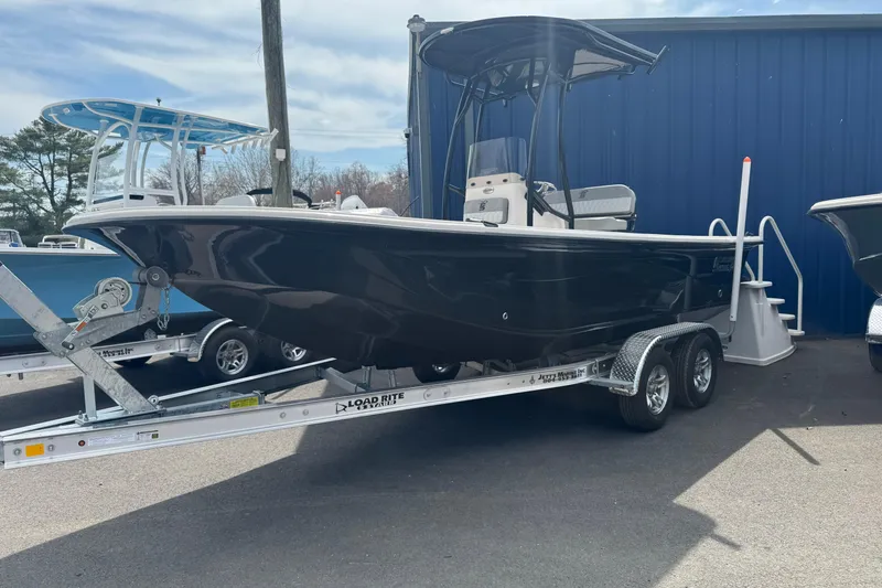 The Image of 2026 Carolina Skiff 21 LS boat on trailer, parked outdoors near blue building. - 0